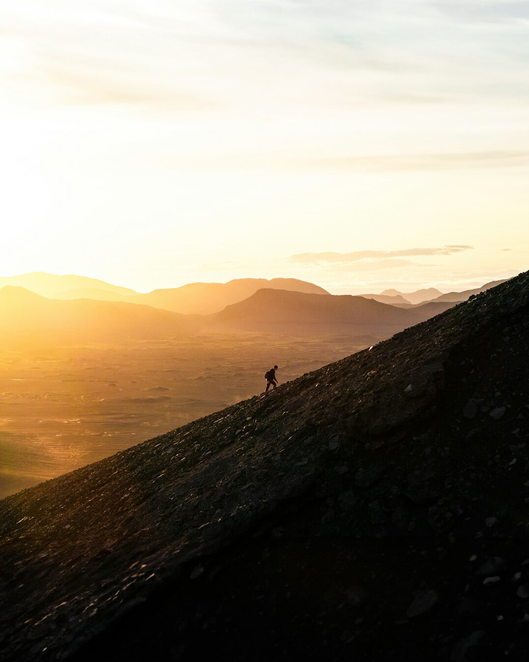 person climbing mountain at sunrise
